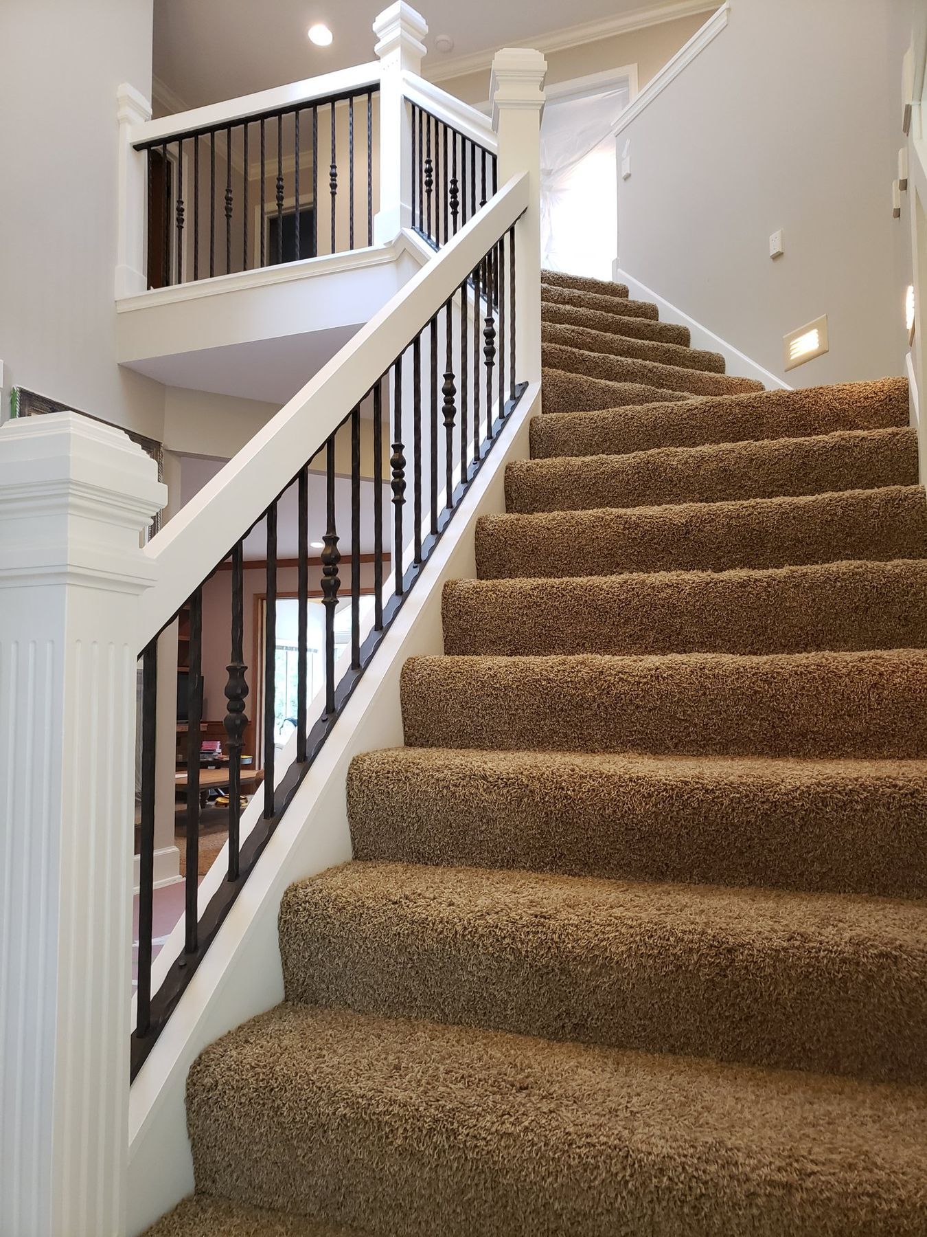 Staircase with white skirt board and spindles and a dark handrail