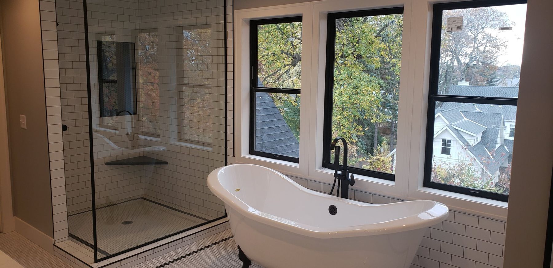 Primary bath with a freestanding tub under black-framed windows