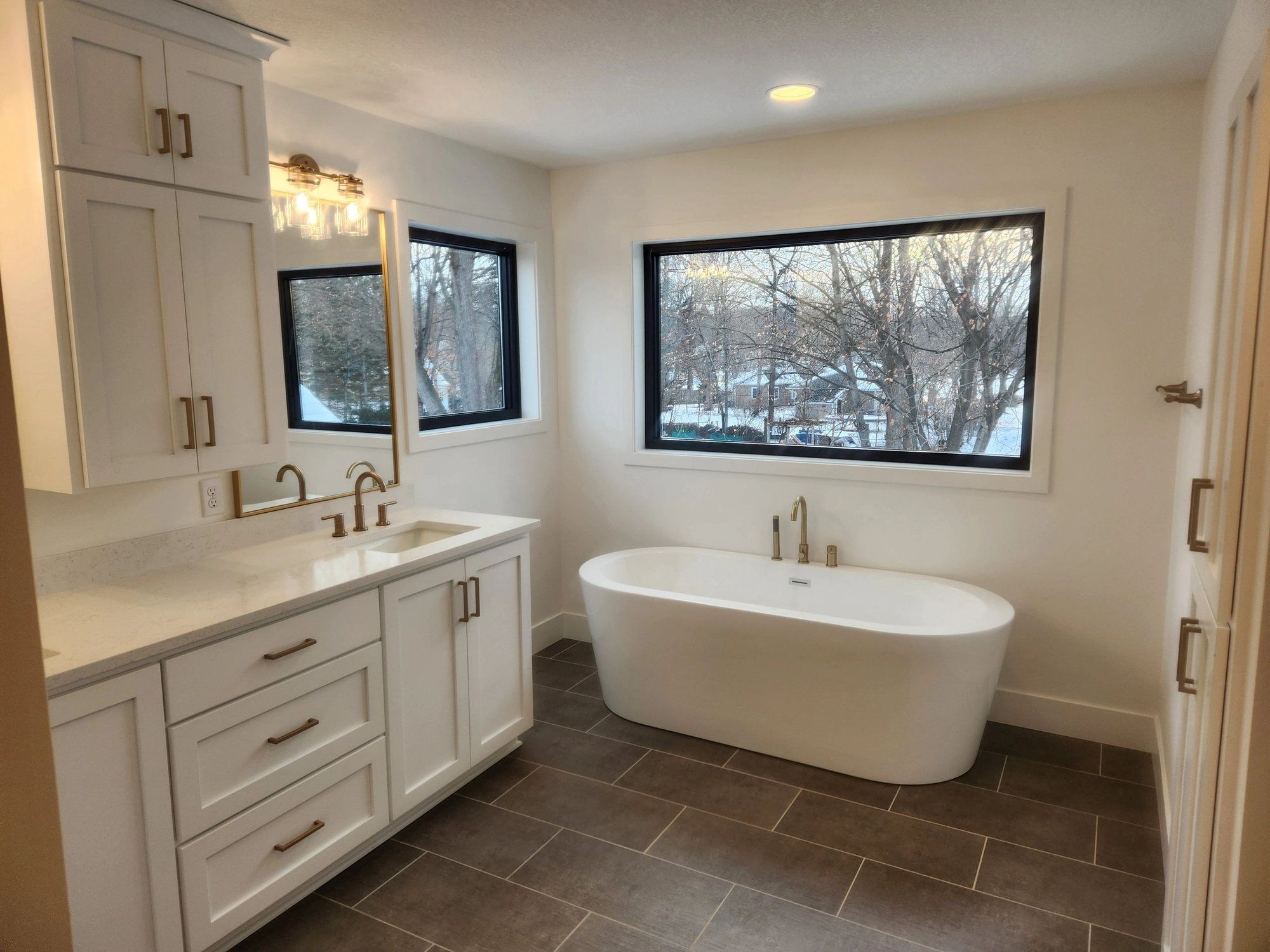 Bright bathroom with white painted cabinetry and freestanding tub