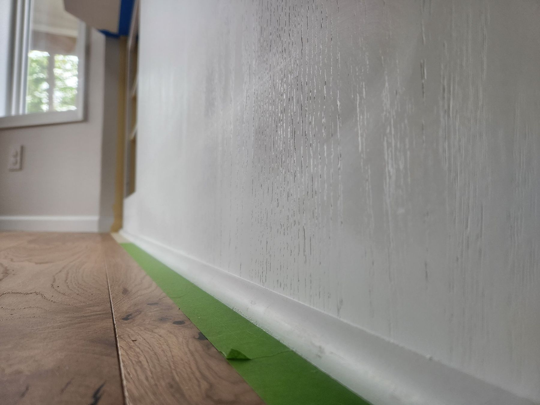 Baseboard primed white along masked flooring