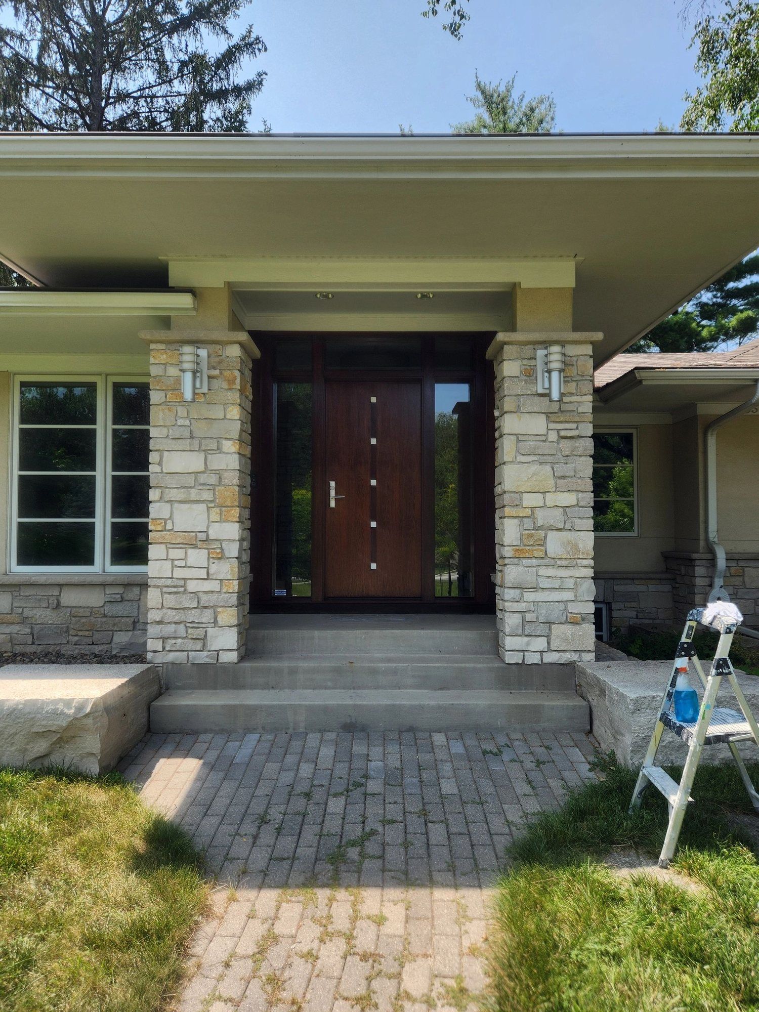Stained wood front entry door with sidelights between stone columns